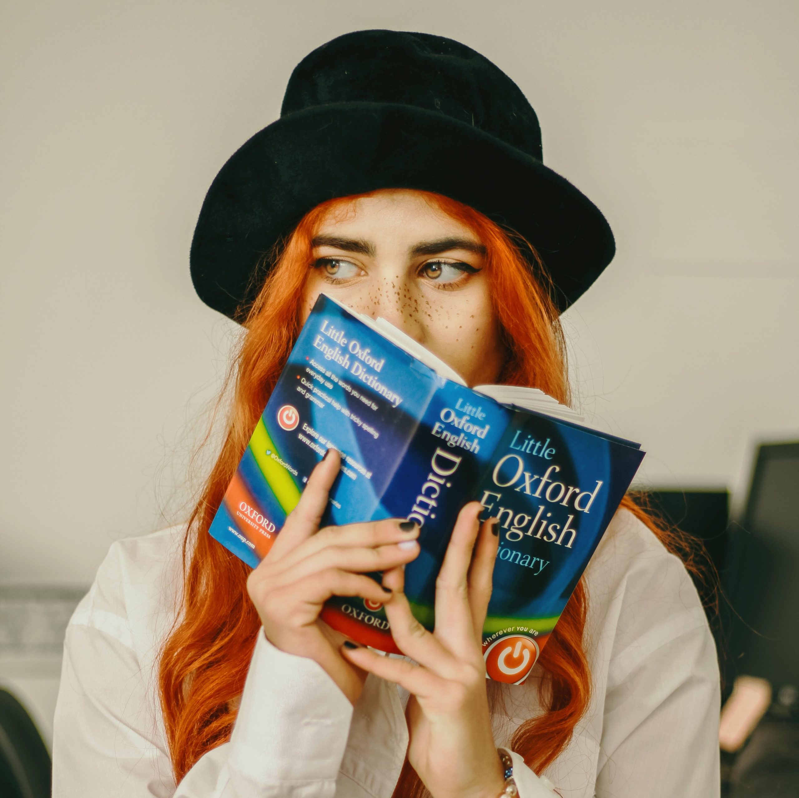 Woman holds English language dictionary over her face