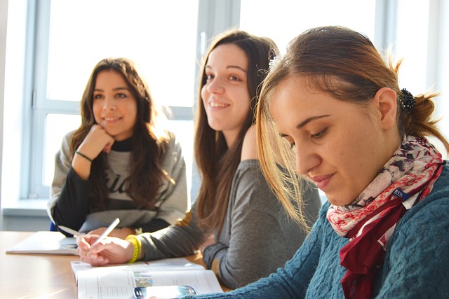 Three girls learning, sitting at a table with open textbooks