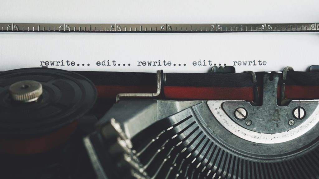 Close-up of a typewriter with white paper that says “rewrite, edit, rewrite, edit,” which is similar to the proposal process.