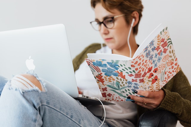 Serious woman using laptop while listening to music in earphones